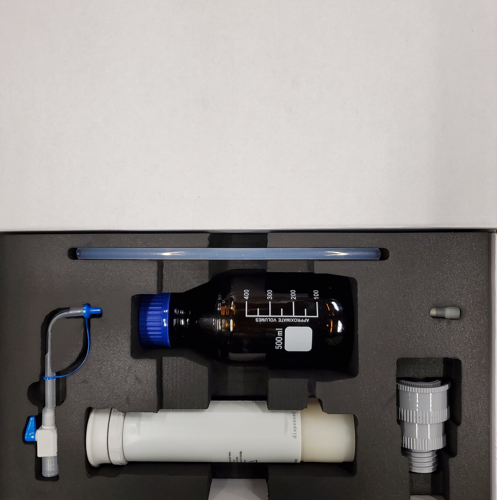 Bottletop dispenser components, including amber bottle, dispenser body, and accessories, organized in a foam-lined box.