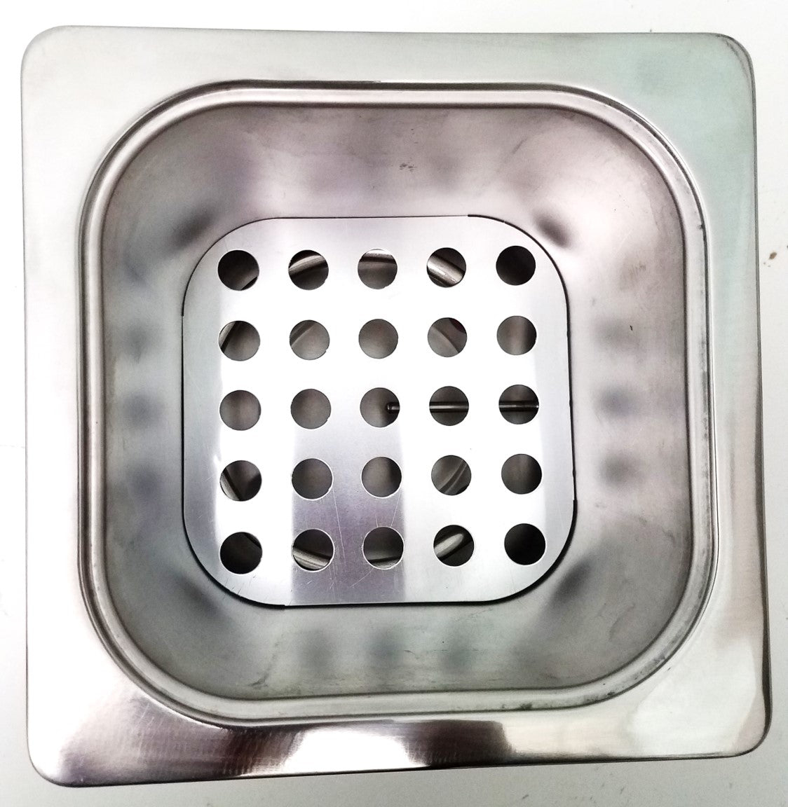 Top-down view of a small, square, stainless steel water bath chamber with a perforated false bottom